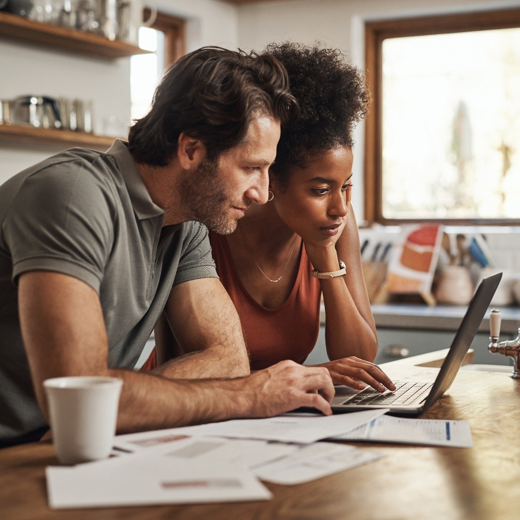 Laptop, Paar und Finanzplanung in einer Küche mit Unterlagen für Budget, Ersparnisse und das Bezahlen von Rechnungen. Interracial, online und Menschen mit Papierkram für Steuern, Hypothek und Hauskreditantrag