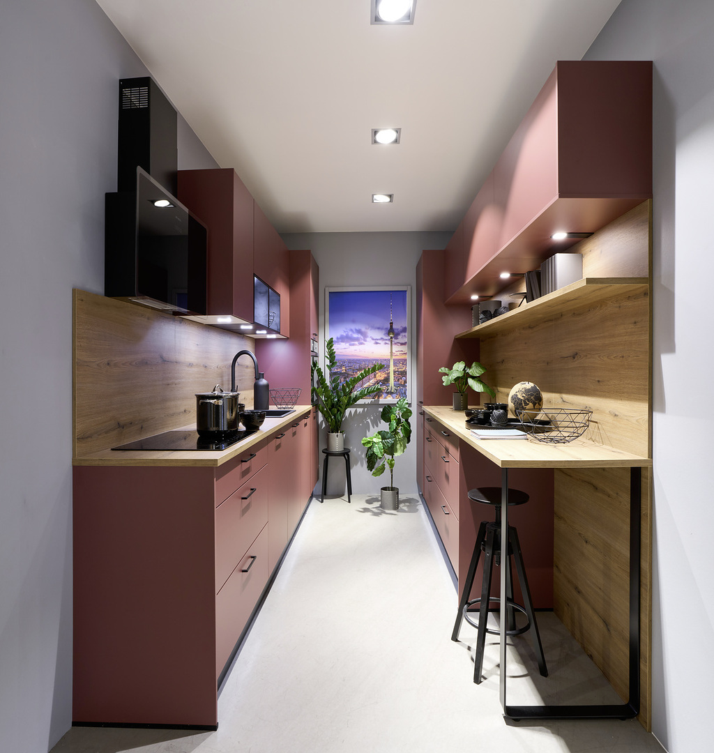 Moderne schmale Küche mit roten Schränken, Holzarbeitsplatten und großen Pflanzen