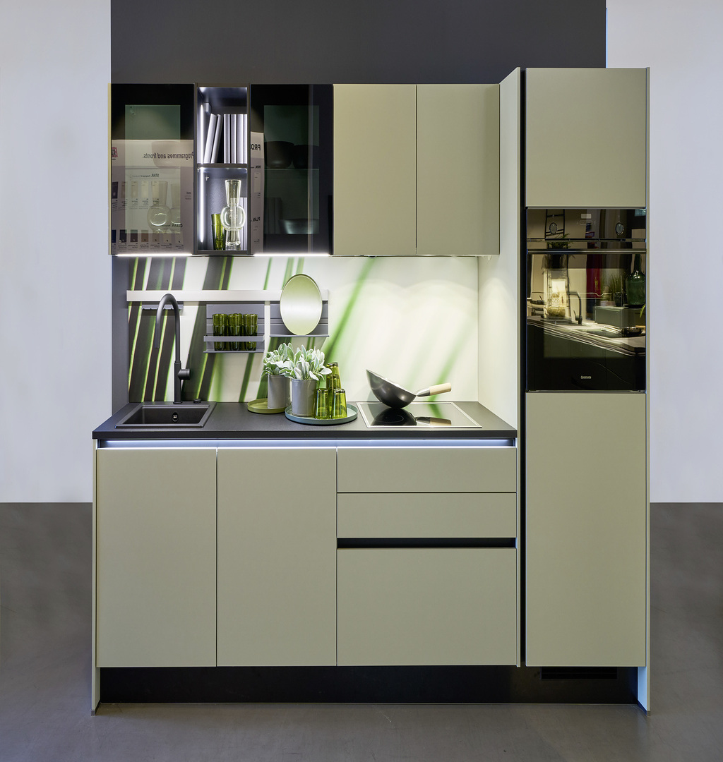 Moderne beige Küche mit schwarzen Details und grüner Rückwand und stilvollem Geschirr