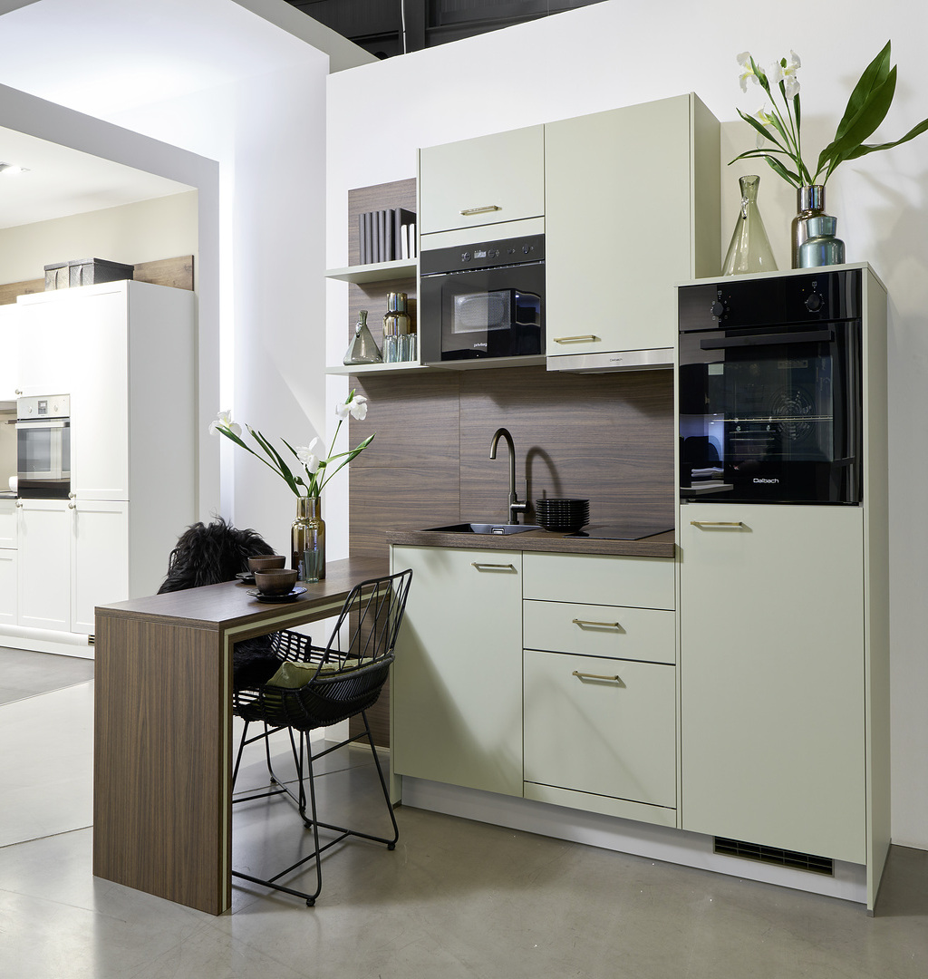 Moderne Küchenecke mit hellen Schränken, dunkler Arbeitsplatte und grünen Pflanzen